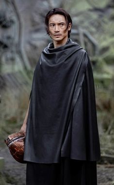 a man wearing a black cape and holding a baseball glove