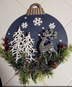 a christmas ornament hanging on the wall with snowflakes and pine cones