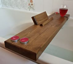 two red candles sit on a wooden table next to a bathtub