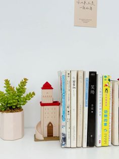 books are lined up on a shelf next to a potted plant and bookend