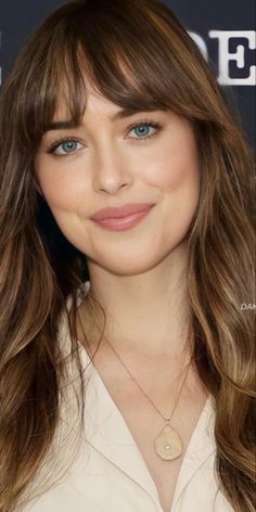 a close up of a person with long hair and blue eyes wearing a white shirt