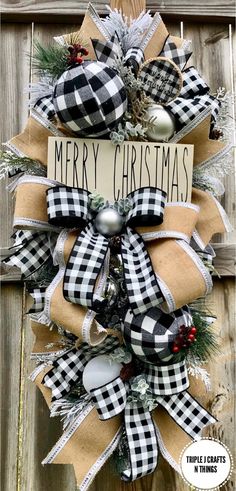 a black and white christmas wreath hanging on a wooden fence with the words merry christmas