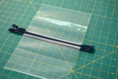 a piece of clear plastic sitting on top of a green cutting mat with scissors and tape