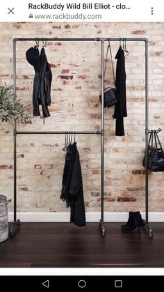 a rack with clothes hanging on it in front of a brick wall and wooden floor