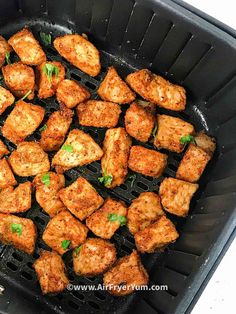 chicken cubes cooking in a skillet with parsley on the top and green garnish