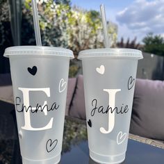 two plastic cups sitting on top of a table with the words d and f painted on them