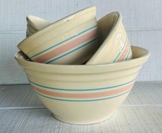 four ceramic bowls stacked on top of each other in front of a white wall with blue and pink stripes