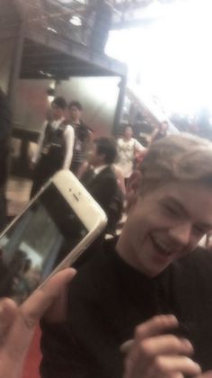 a man is holding up his cell phone in front of him and smiling at the camera