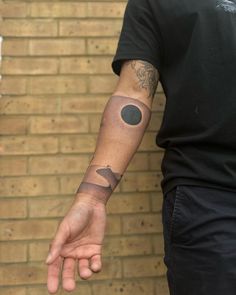 a man with a tattoo on his arm is holding out his hand to the camera