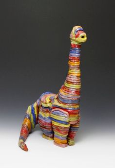 a colorful giraffe statue made out of strips of colored paper on a gray background