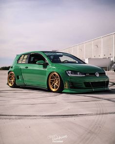 a green car with gold rims parked in an empty lot