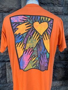 an orange t - shirt with hand prints on the chest and heart at the center