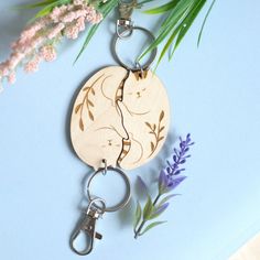 a wooden keychain with two cats on it next to some flowers and leaves