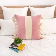 a bed with pillows, books and a potted plant