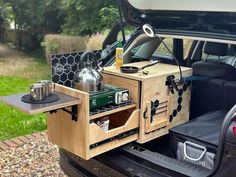 an open trunk in the back of a car with tea kettles and cups on it