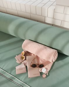 a pair of sunglasses laying on top of a bed next to a pink towel and other items