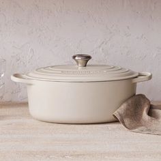 a white casserole dish with a wooden spoon next to it on a table