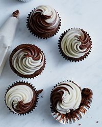 chocolate cupcakes with white frosting and sprinkles on a marble surface