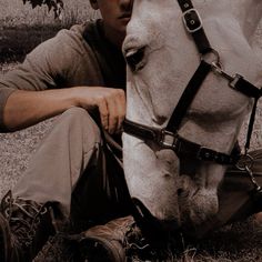 a man kneeling down next to a white horse