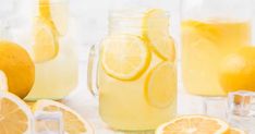 two mason jars filled with lemonade sitting on top of a cutting board next to sliced lemons