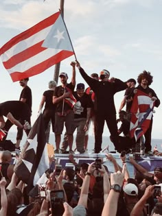 a group of people standing on top of a boat holding american and british flags in the air