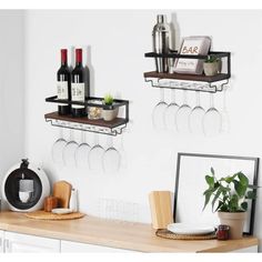 two wine glasses are hanging on the wall next to a shelf with bottles and glasses