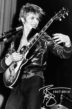 a man holding a guitar while standing next to a microphone