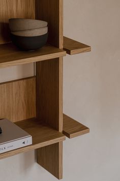 a bookshelf with a bowl on top of it and a book in the middle