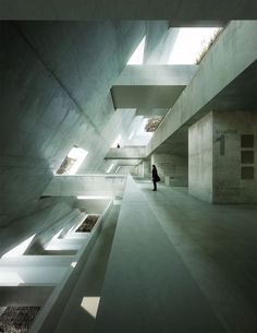 a person standing in an empty building with skylights on the ceiling and stairs leading up to it