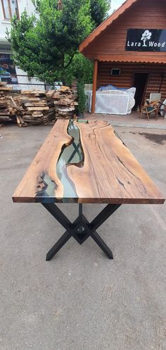 a table made out of wood and metal with a river running through the center, in front of a building