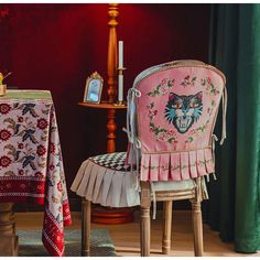 a pink chair with a cat on the back and a table with a mirror behind it