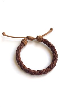 a brown leather bracelet on a white background with the cord attached to it and two small beads