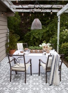 an outdoor dining area with white table cloths, chairs and lights hanging from the ceiling