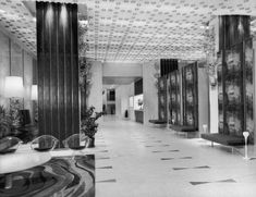 a black and white photo of a lobby with art work on the walls, floor to ceiling