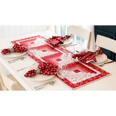 the table is set with red and white place mats, silverware, and napkins