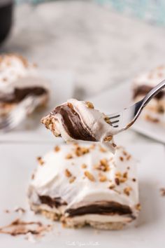 a piece of cake with white frosting and chocolate shavings on top is being held by a fork