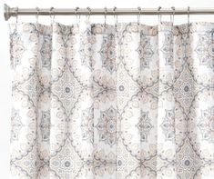 a curtain with an ornate pattern hanging from a metal rod, in front of a white wall