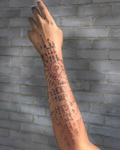 a person's arm with some writing on it and a brick wall in the background