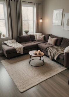 a living room with a sectional couch, coffee table and two lamps on the windowsill