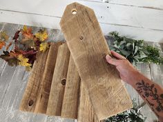 a person holding a piece of wood on top of a wooden floor next to flowers