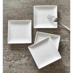 three white square dishes with forks on the side and one empty plate in front of them