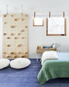 a bedroom with blue carpet, white walls and green bedspread in front of a climbing wall