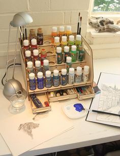 an artist's desk with various paints and supplies on it, including a lamp