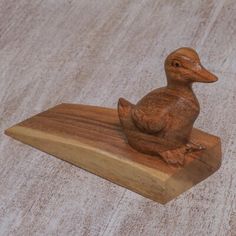 a wooden duck sitting on top of a piece of wood