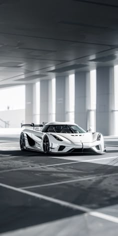 a white sports car is parked in an empty parking garage with no one around it