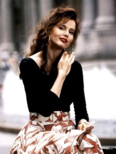 a woman sitting on top of a bench in front of a building holding her hand to her face