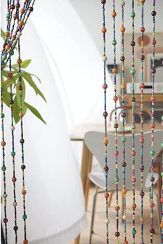 colorful beads hanging from the ceiling next to a potted plant in a living room