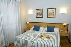 a hotel room with blue and white striped bedspread, two framed pictures on the wall