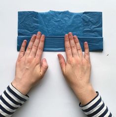 two hands are reaching for something on the floor that is blue and has paper over it