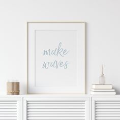 there is a white shelf with books and a framed print on it that says make waves